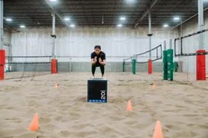 Athlete jumps onto a plyo box during a Beach YYC brand session workout.
